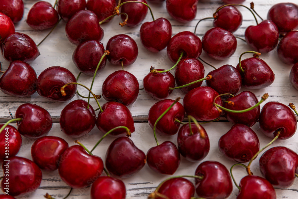 Scattered berries of ripe cherries on a light wooden background. Top view. Seasonal Vitamins. Scattered berries of ripe cherries on a light wooden background. Top view. Seasonal Vitamins.