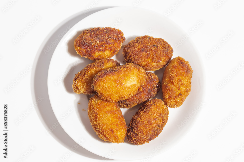 top view of a bunch of crispy homemade croquettes on a white plate