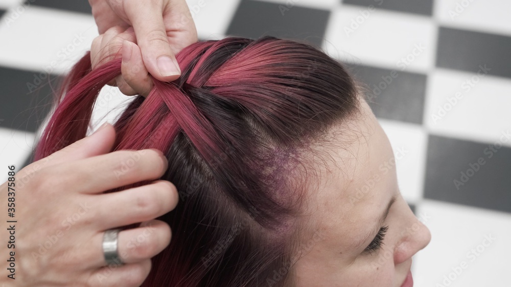 Professional hairdresser plaiting braids to red colored female hair Professional hairdresser plaiting braids to red colored female hair