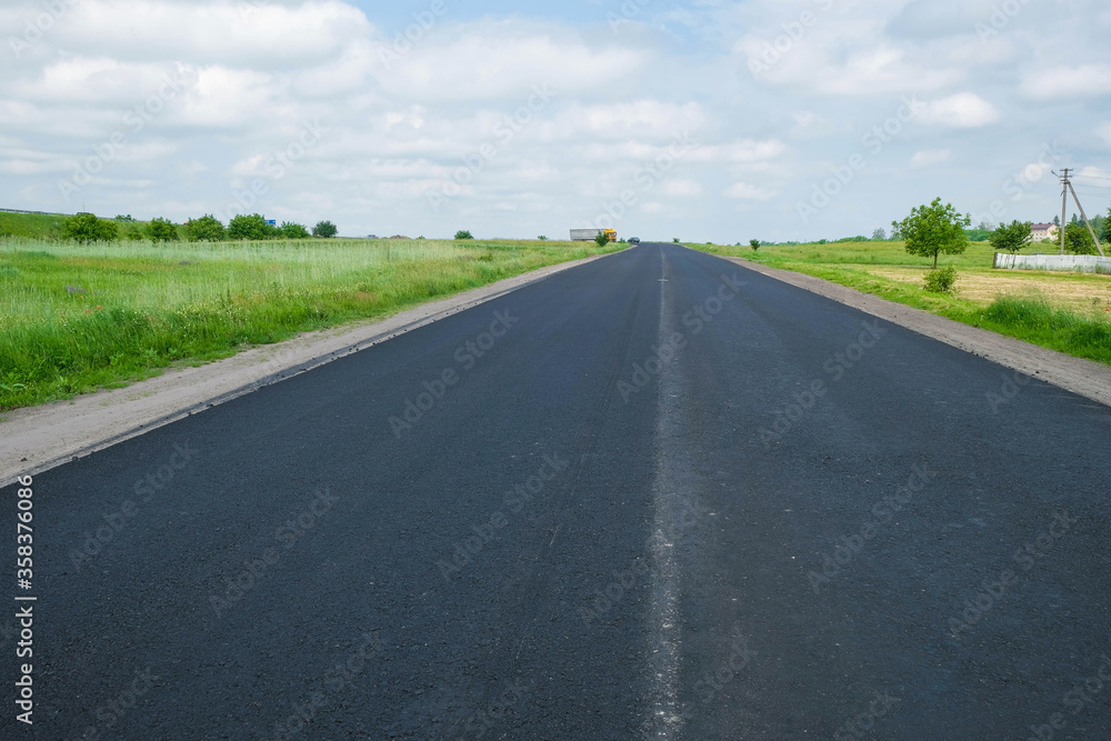 New black asphalt. There is no road marking. Reconstruction of the road in Ukraine on a hot day. Copy space.