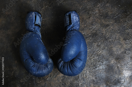 Old blue Boxing gloves on a concrete background. © freeman83