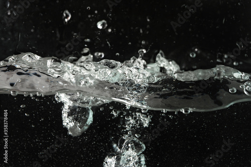 Water splashing as it's poured into aquarium tank, black background © Lubo Ivanko