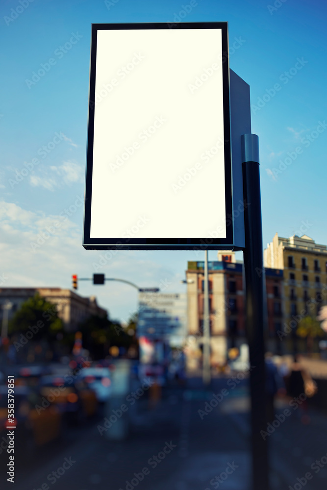 Fototapeta premium Blank billboard with copy space for your text message or content, public information board in the big town, advertising mock up empty banner in metropolitan city at beautiful sunny day, blur effect