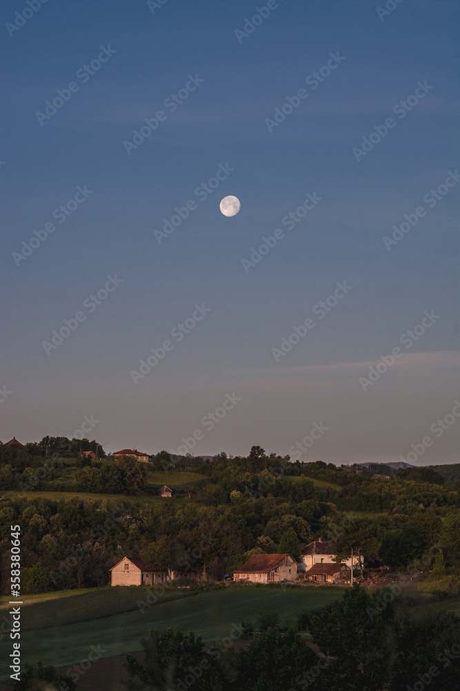 Moon over small farm in the countryside