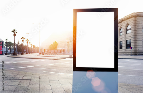 Blank billboard with copy space for your text message or content, outdoors advertising mock up, public information board on city road, flare sun light. Empty Lightbox on urban setting sidelines