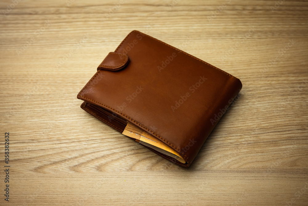 Wallet stuffed with Euro banknotes on the wooden backround Wallet stuffed with Euro banknotes on the wooden backround