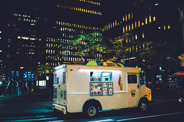 Van automobile with ice cream retail parked on street near building in downtown at evening, business startup with trading sweets via vehicle truck traveling in city distributing food during weekends