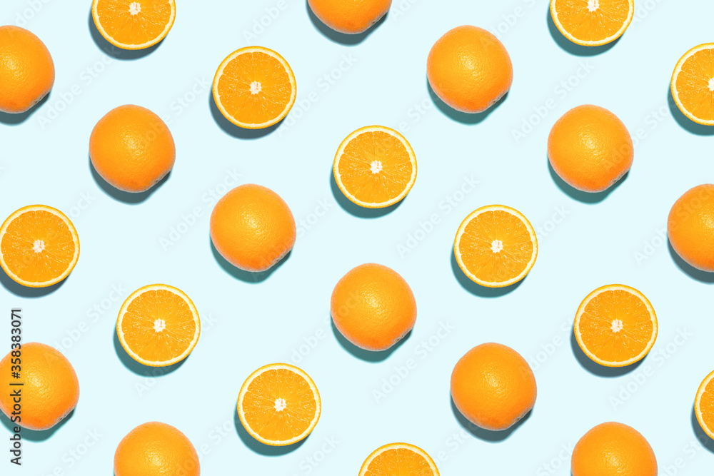 Pattern made of bright oranges in sunlight on blue background. Minimal styled summer concept. Pattern made of bright oranges in sunlight on blue background. Minimal styled summer concept.