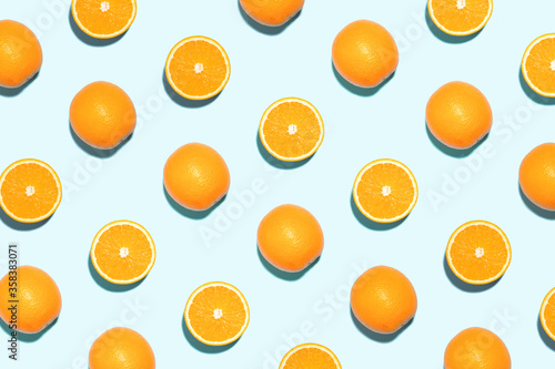 Pattern made of bright oranges in sunlight on blue background. Minimal styled summer concept.