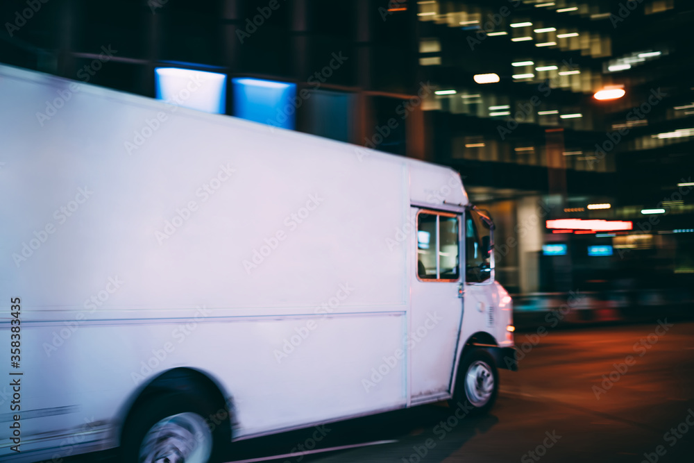Van automobile driving on road in evening downtown transporting and distributing goods for delivery service, mock up copy space on cargo body for logistic company name or logo of startup business Van automobile driving on road in evening downtown transporting and distributing goods for delivery service, mock up copy space on cargo body for logistic company name or logo of startup business