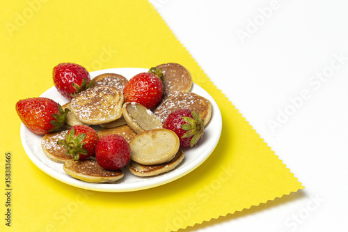 Homemade cereals mini pancake with yogurt, honey and strawberries on colorful background.