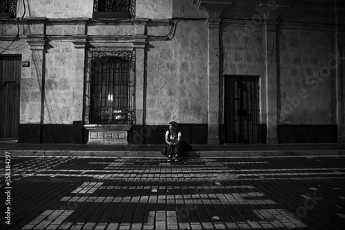 young woman sitting in the sidewalk at night