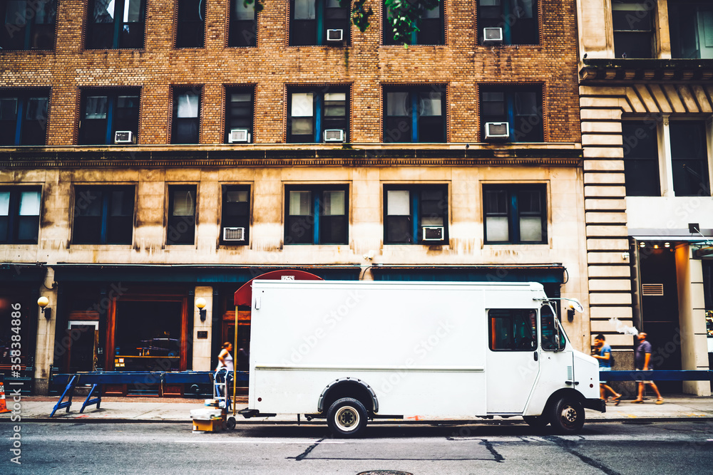 Fototapeta premium White van automobile for relocation and delivery parked on city street near building, cargo of logistic company with moc up area for distribution and shipping corporate name or logo in downtown
