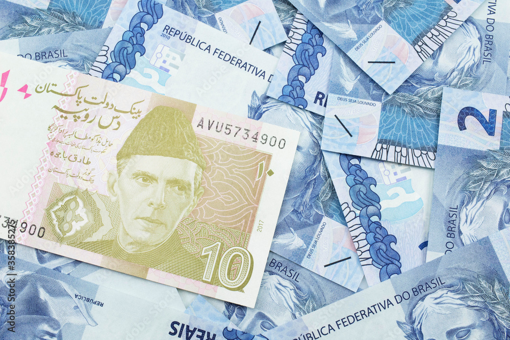 Fototapeta premium A close up image of a gray and pink ten Pakistani rupee bank note with Brazilian two reais bank notes in macro