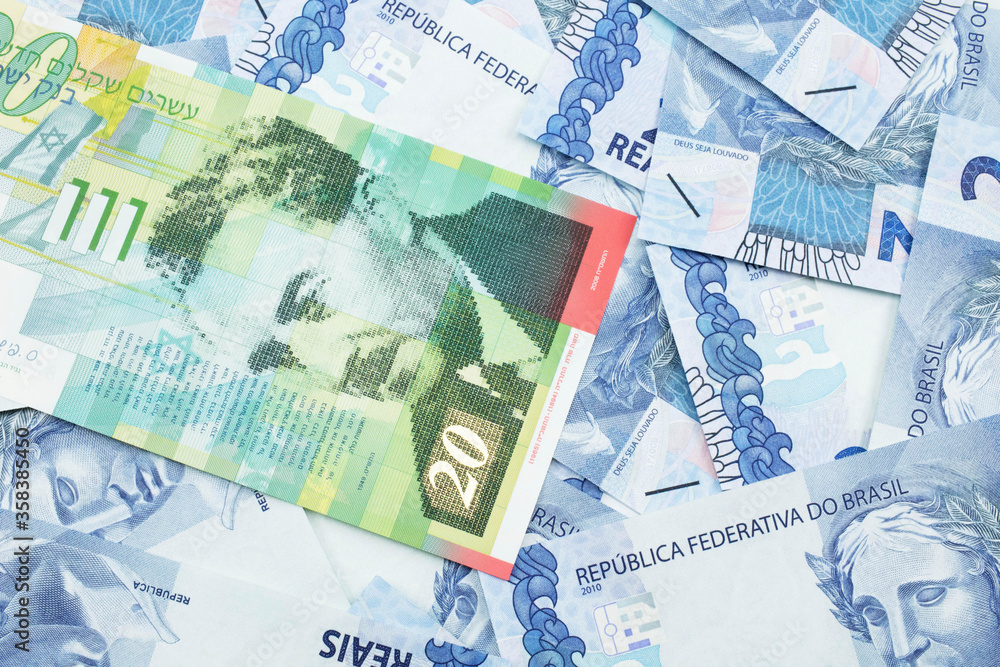 A close up image of a twenty shekel bank note from Israel on a background of Brazilian two reais bank notes in macro A close up image of a twenty shekel bank note from Israel on a background of Brazilian two reais bank notes in macro