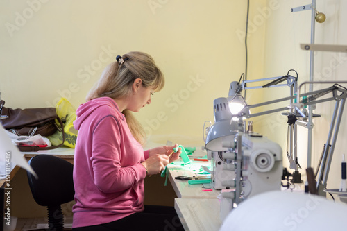 Professional seamstress makes an element of clothing in the workplace