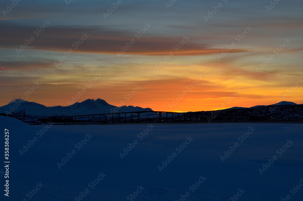 vibrant colourful dawn sky sunset over mountain in winter with tromsoe city island and bridge