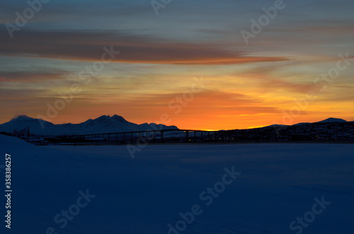 vibrant colourful dawn sky sunset over mountain in winter with tromsoe city island and bridge