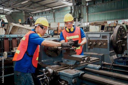 Engineer or mechanical worker with yellow safety helmet checking on production in a factory. Industrial, Mechanic, Engineering Concept. 