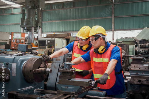 Engineer or mechanical worker with yellow safety helmet checking on production in a factory. Industrial, Mechanic, Engineering Concept. 