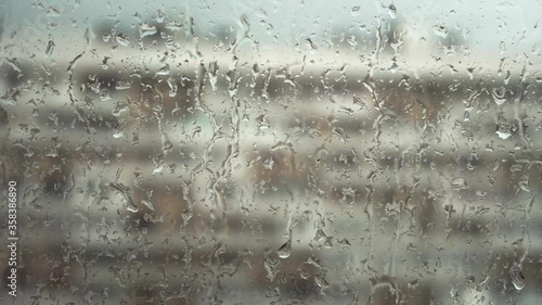 City rain: Close-up of raindrops on window glass. Pan to left.
Handheld shot.