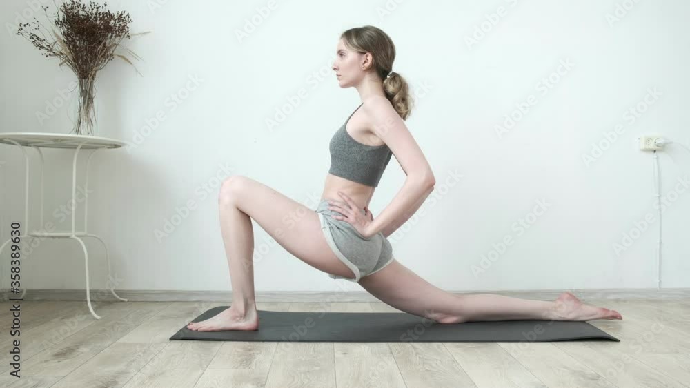young slim girl with ponytail in sportswear doing stretching exercise on mat in bright room. sexy fit female training at home. sports, fitness training, healthy lifestyle, stretching, pilates, workout young slim girl with ponytail in sportswear doing stretching exercise on mat in bright room. sexy fit female training at home. sports, fitness training, healthy lifestyle, stretching, pilates, workout