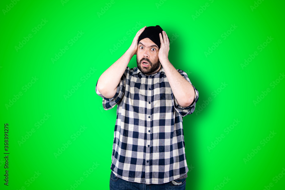 Portrait of a puzzled bearded man holding hands on his head isolated over chroma background Portrait of a puzzled bearded man holding hands on his head isolated over chroma background