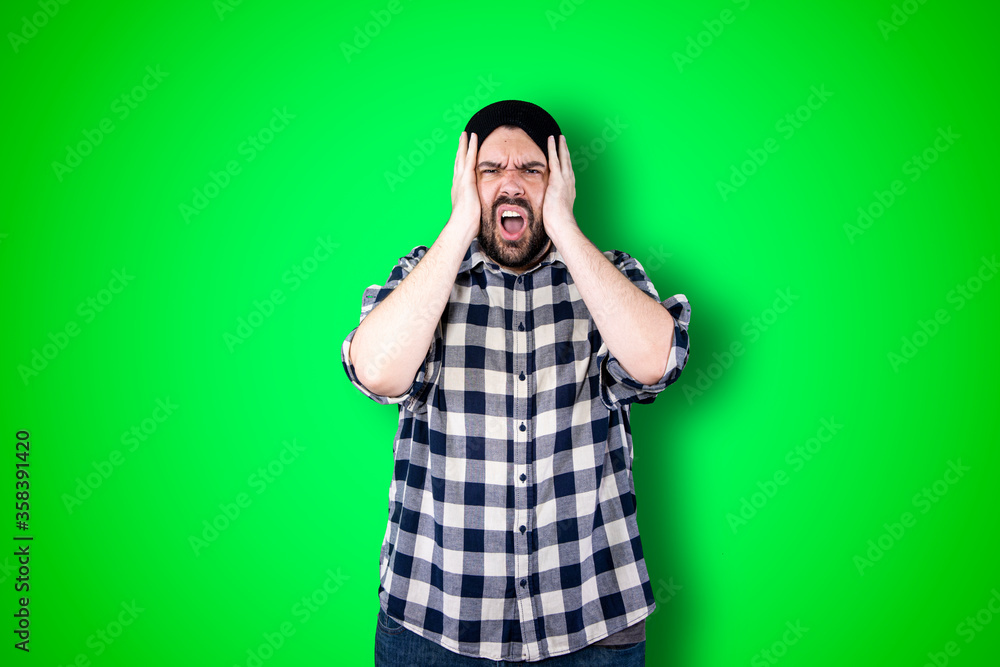 Portrait of a puzzled bearded man holding hands on his head isolated over chroma background Portrait of a puzzled bearded man holding hands on his head isolated over chroma background