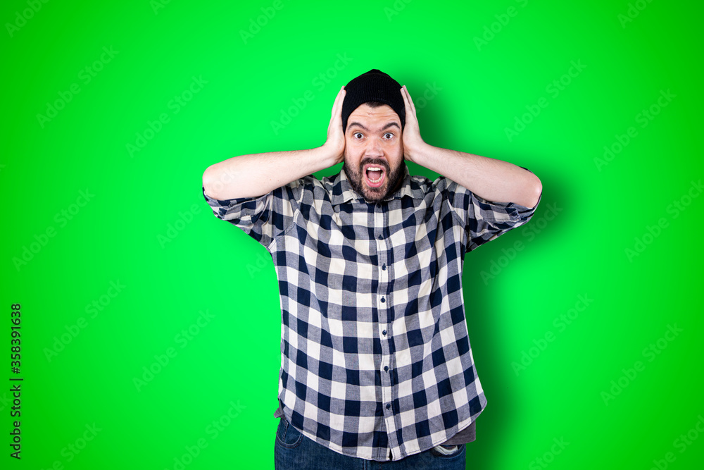 Portrait of a puzzled bearded man holding hands on his head isolated over chroma background Portrait of a puzzled bearded man holding hands on his head isolated over chroma background