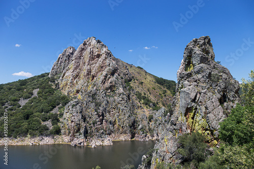 Landscape of rocks and river with vultures in the sky
