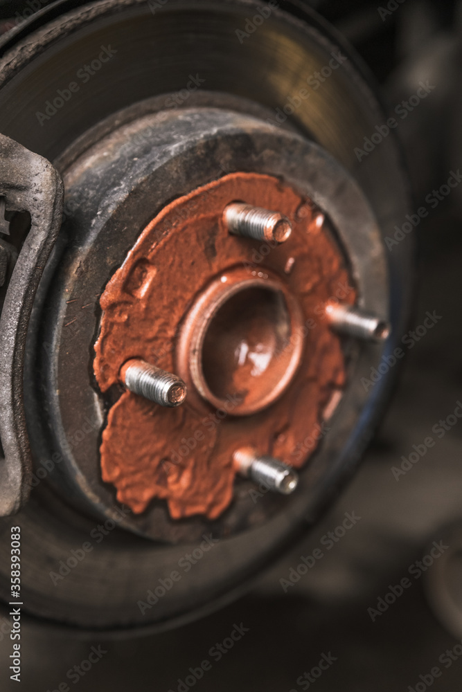 Old rusty worn brake discs are coated with copper grease in a passenger car. Car on a lift in a car service
