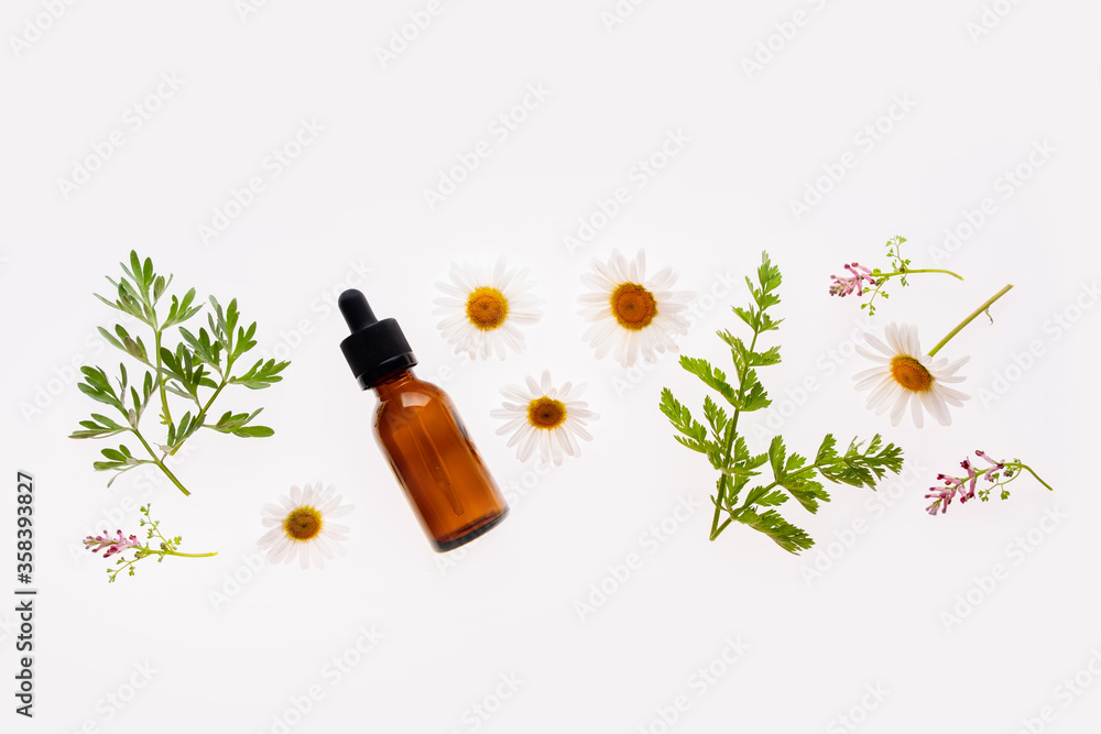 Сhamomile flowers and cosmetic bottle of essential oil on white background, top view.concept of natural cosmetics or alternative medicine Сhamomile flowers and cosmetic bottle of essential oil on white background, top view.concept of natural cosmetics or alternative medicine