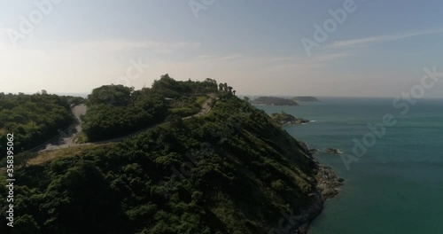 A cape with a forest, a rocky coast, two motor boats in the distance sail to the beach. The stone sticks out of the water. Small sandy beach