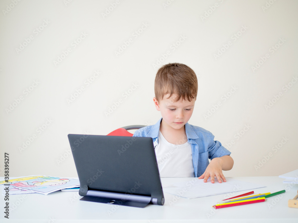 Online lessons For elementary school students. Kid watching a webcast video lesson on a tablet at home and learning to draw Online lessons For elementary school students. Kid watching a webcast video lesson on a tablet at home and learning to draw