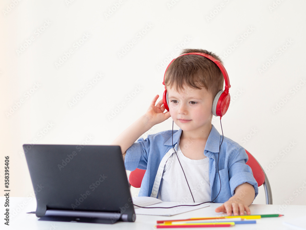 Preschool online lessons app. 4-year kid puts on headphones and going to watch an online lesson on a tablet Preschool online lessons app. 4-year kid puts on headphones and going to watch an online lesson on a tablet