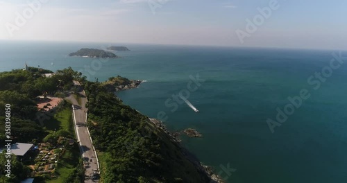 Shore with a stella. A motor boat is sailing off the coast. The islands are visible on the horizon. On the coast road and buildings