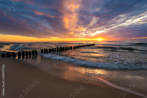 Fototapeta Naklejka Na Ścianę i Meble -  beautiful sunset on the Baltic Sea, waves washing the old wooden breakwaters