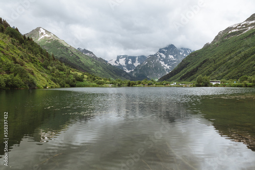 Ripple reflection in the alpine lake Tumanly Kol' with high snowy peaks and storm clouds in the background, Teberda Nature Reserve in Caucasus Mountains photo