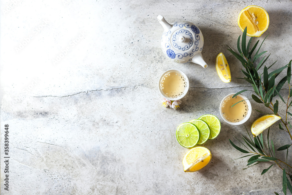 Tea set, lemon, mint and flowers on a light concrete background. View from above. Tea party concept. Tea set, lemon, mint and flowers on a light concrete background. View from above. Tea party concept.
