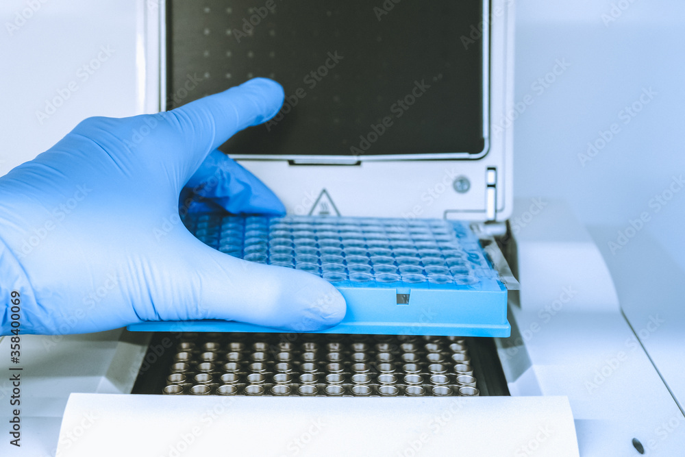 Research scientist putting test 96 well platte into real-time pcr machine