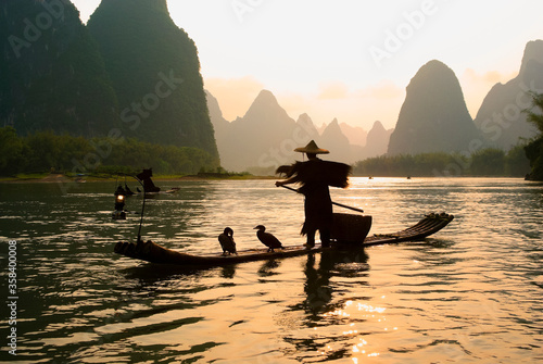 Silhouette of cormorant fisherman on the Li River (Lijiang) with karst peaks in the background at sunset, near Xingping, Guangxi Province, China
