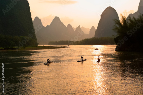 Silhouette of cormorant fishermen on the Li River (Lijiang) with karst peaks in the background at sunset, near Xingping, Guangxi Province, China