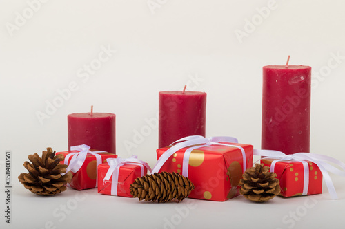 Christmas holidays composition with decorations, red candles, pine cones and gift boxes on white background with copy space for your text. 