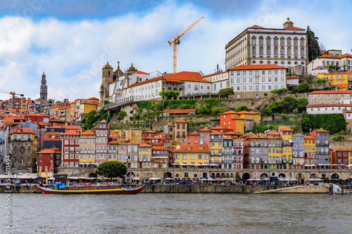 Facades of traditional houses with azulejo tile in Ribeira and tourist rabelo boats across the Douro in Porto, Portugal