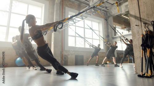 Stronger than yesterday. Full-length shot of men and women doing fitness training exercises at industrial gym. Push-up, group workout concept