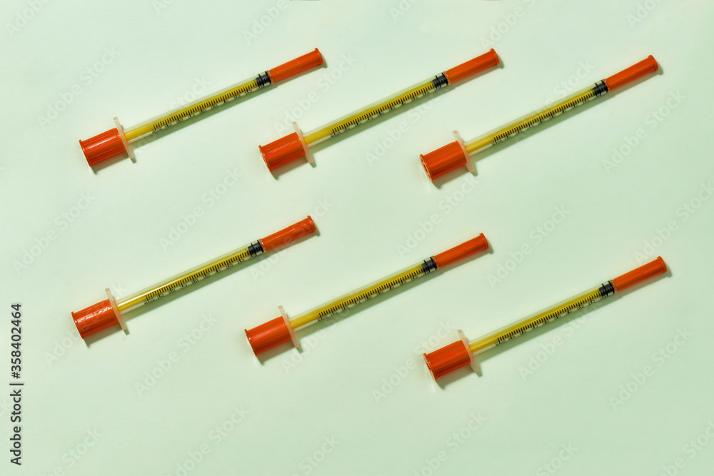 Top view of insulin syringes for diabetes lying diagonally isolated over light background. Injection medicine concept Top view of insulin syringes for diabetes lying diagonally isolated over light background. Injection medicine concept