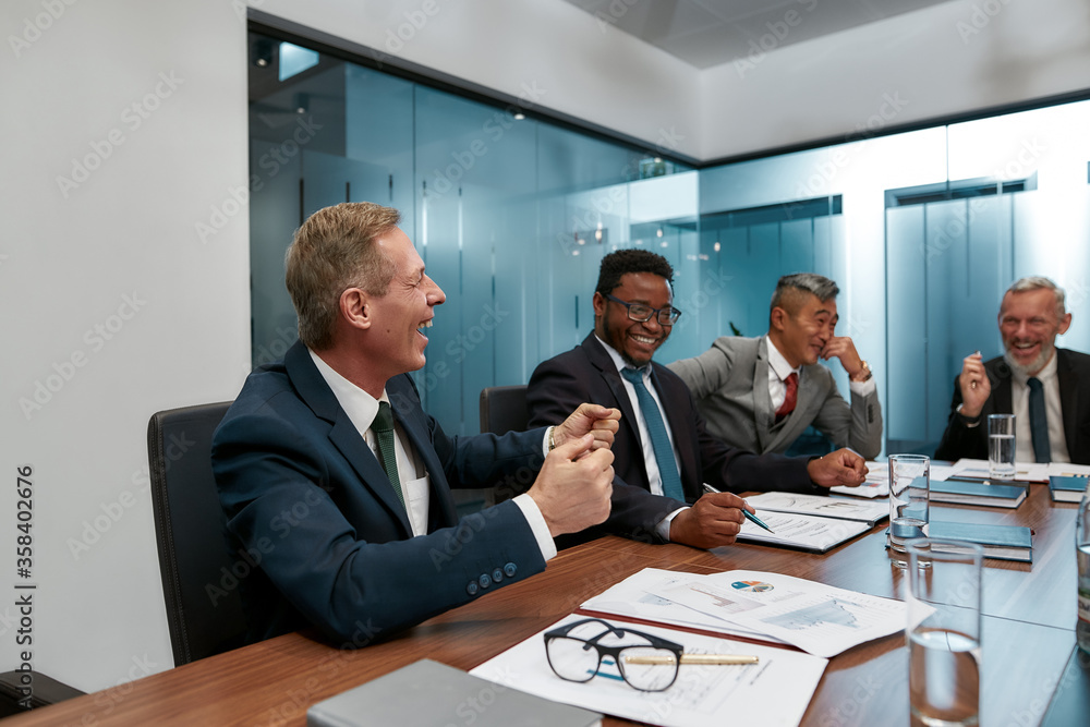 Strong team. Multicultural business people in formal wear discussing something and smiling while having a meeting in the modern office Strong team. Multicultural business people in formal wear discussing something and smiling while having a meeting in the modern office