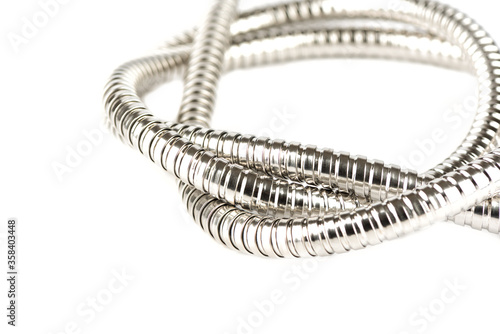 Selective focus. Twisted metal corrugated shower hose on a white background.