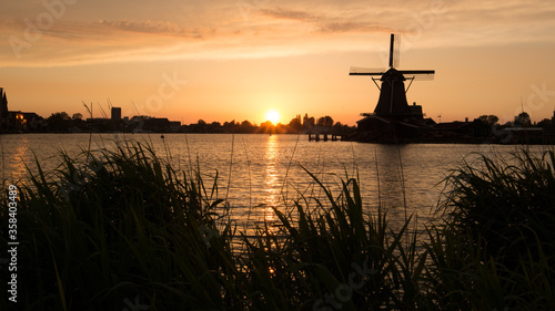 Dutch windmill silhouette next to a lake at sunset