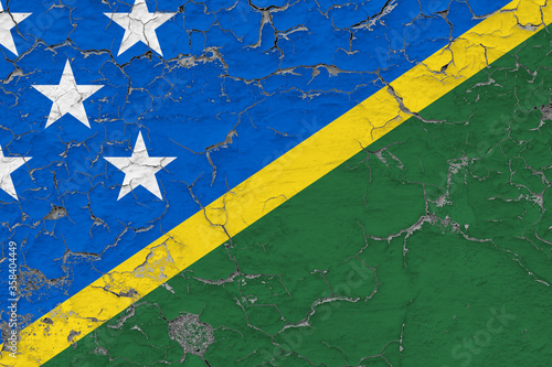 Solomon Islands flag close up grungy, damaged and weathered on wall peeling off paint to see inside surface. Vintage concept.